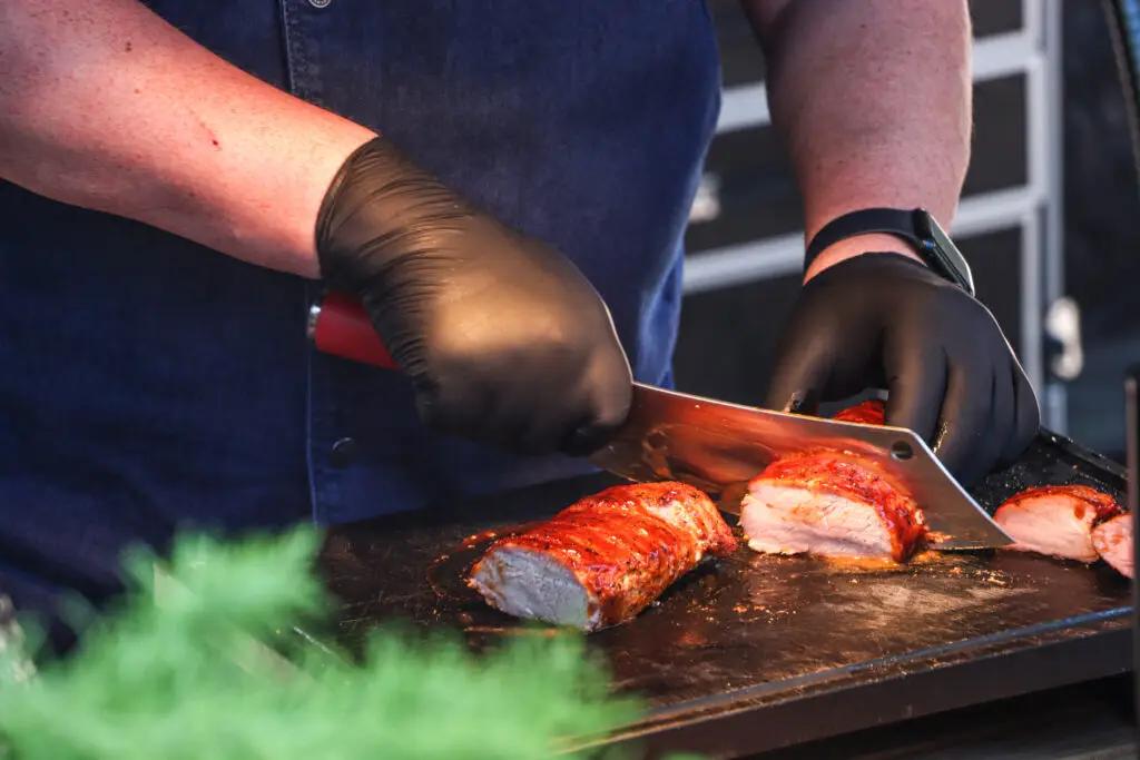 Ribs werden auf der Plancha geschnitten, Rauch steigt auf