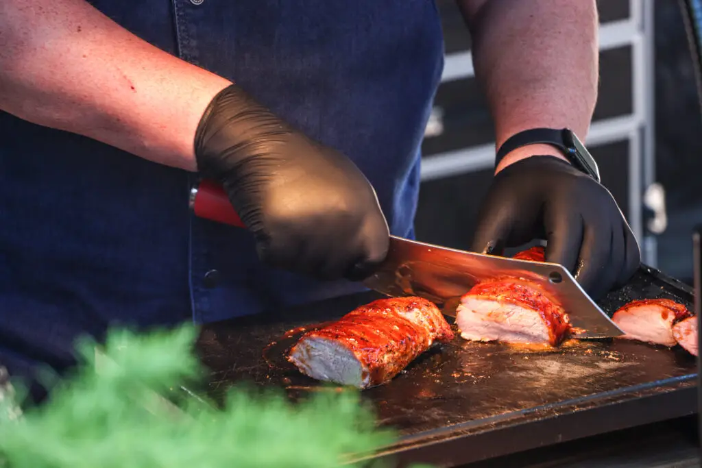 Ribs werden auf der Plancha geschnitten, Rauch steigt auf
